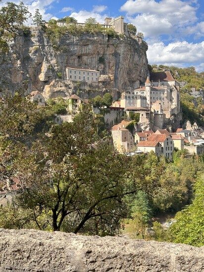 Rocamadour village in the Lot department, medieval houses stacked on top of each other on a cliffside overlooking the green valley.
