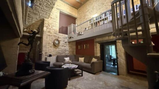 Salon bibliothèque voûté avec escalier en colimaçon et mezzanine aux Hauts de Sauliès